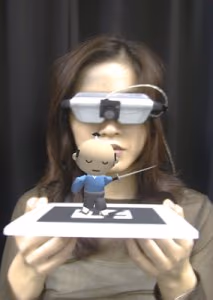 ARToolKit: a 3D virtual character standing on a real card seen through a head-mounted display, an early marker-based AR example