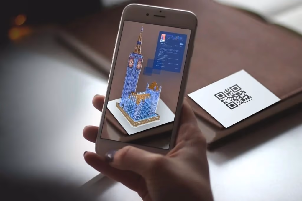 Marker-based AR: a smartphone recognizes a printed QR code and renders a 3D building model on top of it