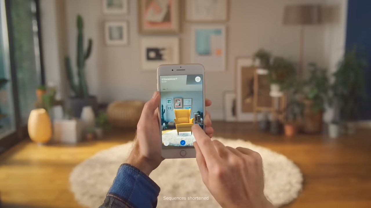 Markerless AR example IKEA Place: placing a virtual yellow armchair on the floor of a real room through a smartphone