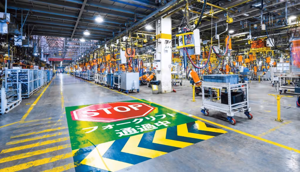 A projection-based AR example: a glowing, moving 'STOP — forklift passing' safety sign projected onto a factory floor